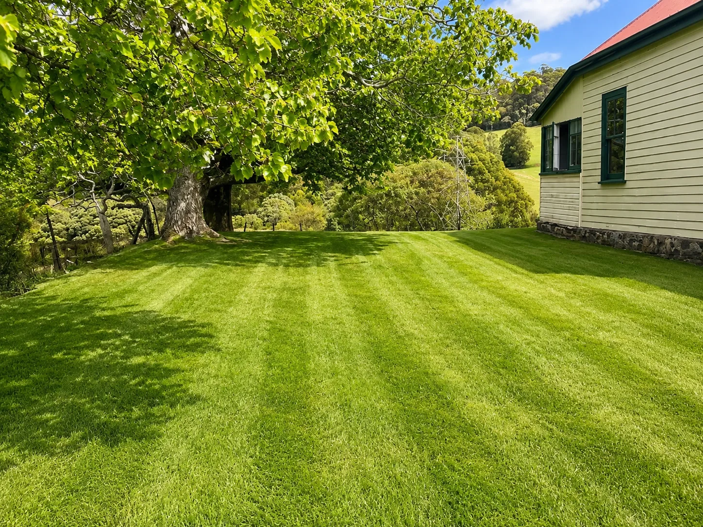 Freshly mowed striped lawn beside a Tasmanian cottage — property tidy-up before inspection day